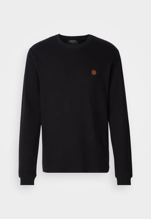 Pull noir à manches longues avec col rond, featuring des poignets côtelés et un petit logo circulaire marron sur la poitrine gauche.