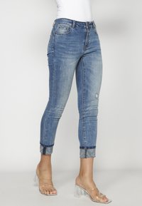 Smala jeans i ljusblå denim med en blekt finish. Uppvikta fållar med ett mönstrat accent. Bärs med transparenta klacksandaler.