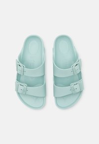 Ανοιχτό γαλάζιες σαγιονάρες με δύο ρυθμιζόμενους ιμάντες που διαθέτουν αγκράφες. Κατασκευασμένες από ομαλή, ανθεκτική ύλη με ανατομική σόλα.