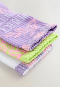 Fyra par stickade strumpor: lila med mönster, rosa och gröna med abstrakta mönster, samt ett vitt par med glittriga detaljer.