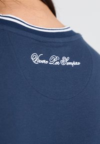 Marineblå bomulds skjorte med rund halsudskæring, med en hvid stribet detalje og broderet tekst "Vivere Per Sempre" på ryggen.