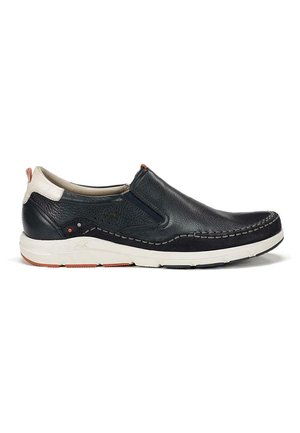 Zapato negro de cuero deslizable con una suela blanca, presentando costuras decorativas y un acento naranja en el talón. Superficies lisas y texturizadas.