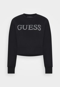 Sweatshirt noir court avec manches longues, poignets et ourlet côtelés, et logo "GUESS" en strass sur la poitrine.