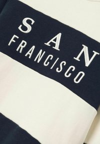 Felpa a righe blu navy e crema con testo ricamato "SAN FRANCISCO." Tessuto morbido, scollatura rotonda e vestibilità allungata.