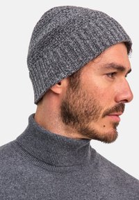 Gray knitted beanie with ribbed texture, soft material, featuring a folded cuff edge. Worn on the head with a subtle sheen.