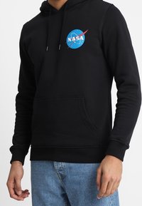 Sudadera negra de mezcla de algodón, con un logo azul de la NASA en el pecho, bolsillo frontal y puños y dobladillo acanalados.