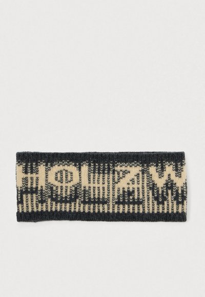 Fascia in maglia con uno schema di colori a contrasto nero e beige e un motivo geometrico. Il testo è integrato nel design.