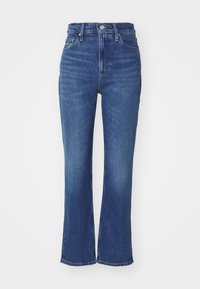 Aukštos juosmens mėlynės džinsai iš denim medžiagos. Yra šiek tiek platesnės apačioje, matoma siuvinėjimas ir klasikinis penkių kišenių dizainas.