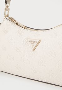 Borsa a tracolla in pelle bianca testurizzata con dettagli in oro e una placca triangolare con logo. Presenta una chiusura con zip e una silhouette curvata.