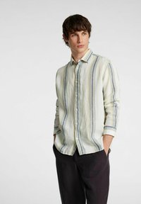 Camicia a maniche lunghe di colore chiaro in lino con righe verticali blu e gialle. Presenta un colletto button-down e chiusura frontale con bottoni.