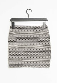 Schwarz-weiß gemusterter Rock mit tailliertem Design. Besitzt geometrische Formen und horizontale Streifen. Hängt an einem schwarzen Plastik-Haken.