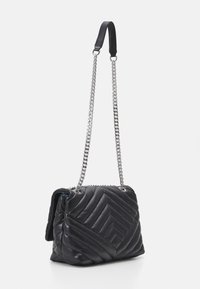 Black quilted leather handbag with a chevron pattern, featuring a dual chain strap and a smooth top handle. Zipper closure detail visible.