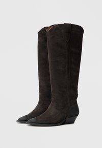 Fekete szarvasbőr térdig érő csizma hegyes orral és enyhén emelt sarokkal. A szár mentén varrott mintázattal és könnyű felvételt segítő füllel rendelkezik.