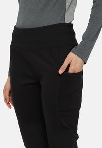 Zwarte stretchstof broek met een hoge tailleband, voorzien van een zijzak met ritssluiting, een gladde textuur en contrasterende stikseldetails.