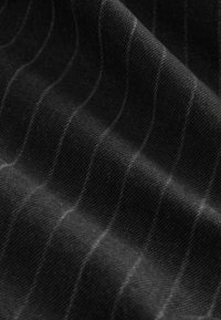 Gros plan sur un tissu noir à fines rayures blanches montrant la texture et des plis délicats.