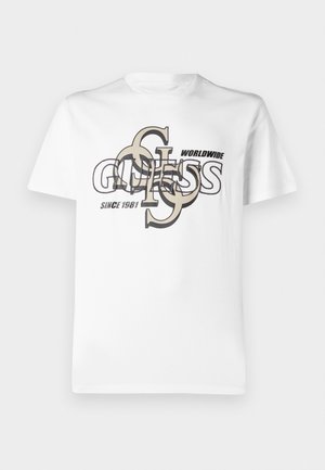 Camiseta de algodón blanca con un diseño gráfico que presenta el texto superpuesto "GUESS" y "WORLDWIDE SINCE 1981" en negro y beige. Mangas cortas.