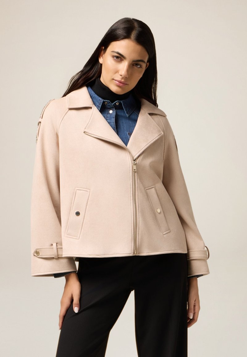 Lichtroze, zachte stoffen jacket met een rits aan de voorkant, brede kraag en zakken. Kenmerkt zich door een ontspannen pasvorm en decoratieve knopen op de mouwen.
