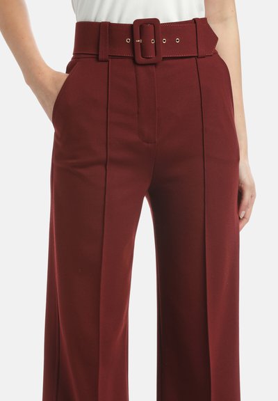Pantaloni burgundy cu talie înaltă și picior larg, având un brâu gros cu cataramă pătrată, buzunare laterale și textură netedă.