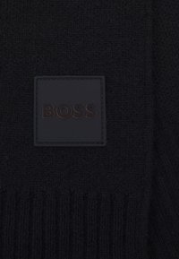 Sciarpa nera lavorata a maglia con una texture a coste e un quadrato in pelle nera con il logo stampato "BOSS."