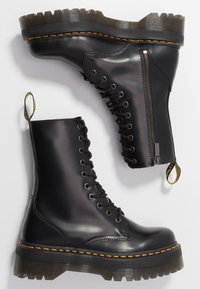 Schwarze Lederstiefeletten mit Schnürdesign, seitlichem Reißverschluss und einer robusten Gummisohle mit strukturiertem Finish und orangefarbenen Nähten.