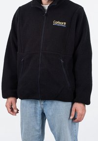 Czarna polarowa kurtka z zamkiem błyskawicznym, dwoma przednimi kieszeniami i wysokim kołnierzem. Wykonana z teksturowanego materiału, z małym logo na piersi.