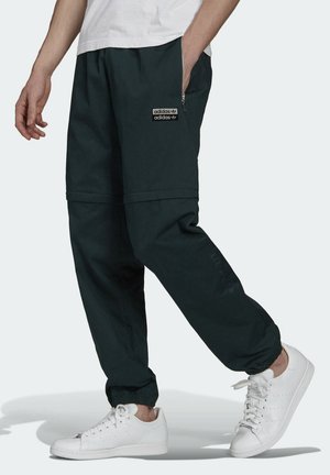 Sorte joggingbukser med elastiske manchetter, sidelommer med lynlås og broderet logo. Sammen med hvide sneakers. Et afslappet, løst design.