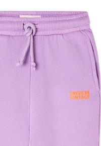 Lavender sweatpants with a textured fabric, featuring an elastic waistband, drawstring, side pockets, and an orange "AMERICAN VINTAGE" logo.