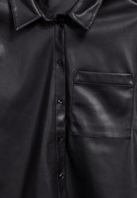 Zwarte faux leren shirt met een puntige kraag, voorzijde met knopen en een enkele zak op de linkerborst. Gladde textuur.