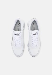 Chaussures de sport blanches avec une tige synthétique lisse, un bout rond et une semelle épaisse. Elles comprennent des lacets, un logo discret et une semelle intérieure rembourrée.