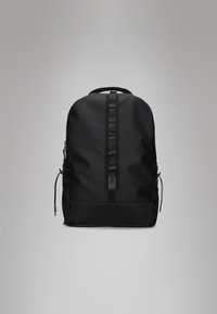 Mochila preta feita de tecido durável, apresentando uma superfície suave, uma alça central, bolsos laterais em malha e um painel inferior texturizado.