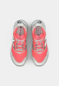 Chaussures de trail avec un dessus rose vif, des accents gris et une semelle texturée. Lacets et détails de marque en noir contrastant.
