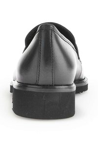 Zwarte leren schoenen met een ronde achterkant en een gladde textuur, uitgerust met een lage, stevige rubberen zool en een subtiele stikselafwerking.