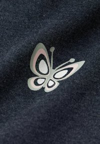 Un tissu sombre à finition texturée présente un motif de papillon multicolore en rose pastel et vert, avec des accents noir et blanc.