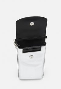 Valkoinen ja musta keinonahkainen pussi hopeisella nepparikiinnityksellä, jossa on sisäosia ja tyylikäs pystysuora muotoilu.