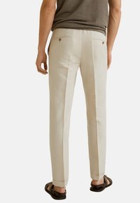 Lichtbeige linnen broek met een rechte snit, voorzien van twee achterzakken met knoopsluitingen en een smalle zoom.