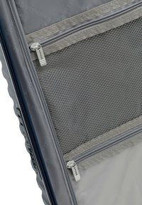 Grijze kofferinterieur met twee gevingerde netcompartimenten en een beveiligingsslot aan de zijkant.