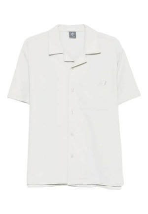 Camicia bianca a maniche corte con bottoni, con un piccolo logo New Balance sul petto a sinistra e un colletto classico.
