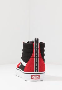 Baskets montantes noires et rouges avec une tige en daim et toile, une bande latérale blanche, un col rembourré et un logo signature sur la languette du talon.