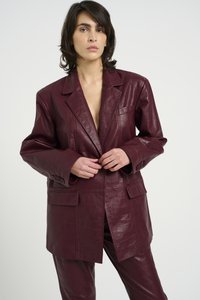 Blazer in eco-pelle bordeaux con texture coccodrillo, dotato di una tasca sul petto, due tasche anteriori e ampi polsini.