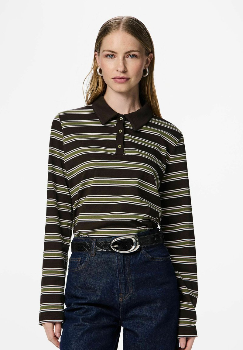 Rudas ilgomis rankovėmis polo marškinėliai su žaliai baltomis juostelėmis, tamsia apykakle ir trijų mygtukų pločiu, derinami su aukštakulnėmis džinsinėmis kelnėmis.