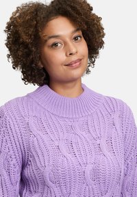 Lila gestrickter Pullover mit einem gerippten Kragen und Wellenmuster. Texturiertes, lässig geschnittenes Design, das aufwendige Nähdetails präsentiert.