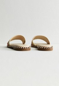Sandalias de punta abierta con suelas marrones, que presentan adornos multicolores decorativos y un diseño de tira simplista, con bordes cosidos y una plantilla plana.