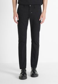 Crne pamučne hlače slim fit kroja, s klasičnim dizajnom od pet džepova, metalnim zatvaranjem na dugme i diskretnim detaljima šivanja.
