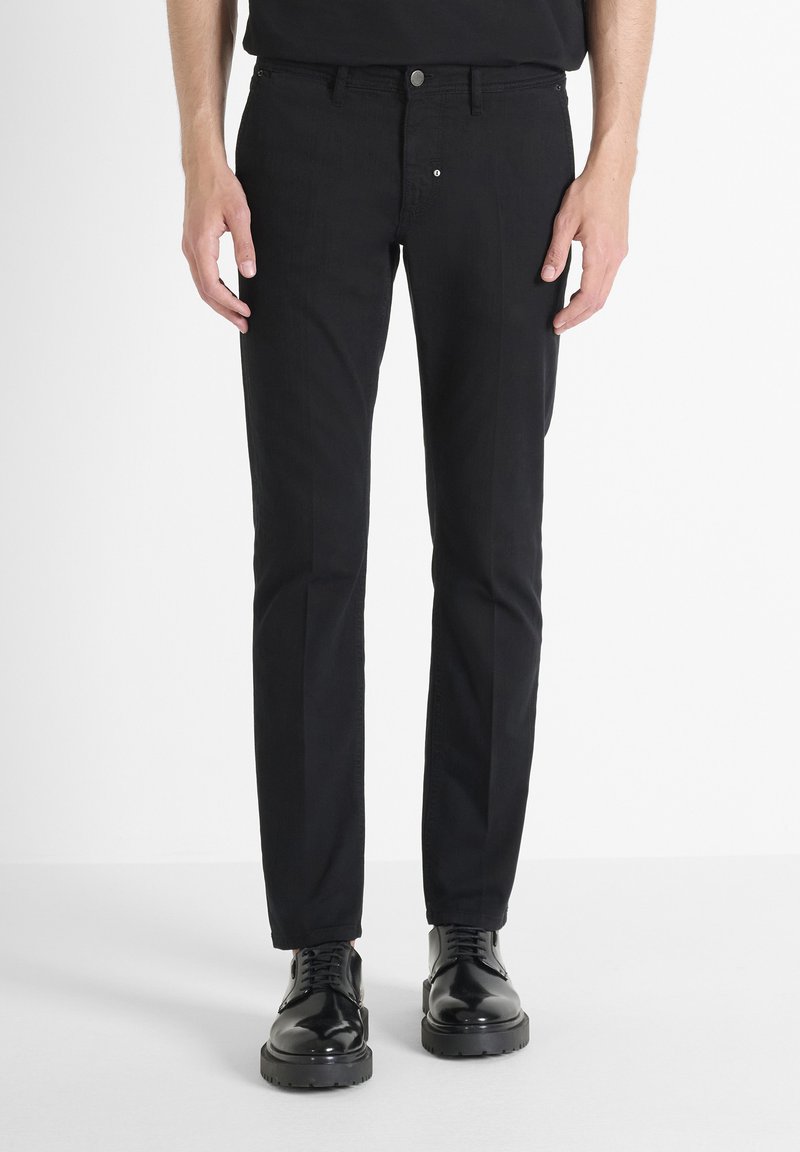 Crne pamučne hlače slim fit kroja, s klasičnim dizajnom od pet džepova, metalnim zatvaranjem na dugme i diskretnim detaljima šivanja.