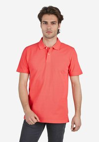 Korallenfarbenes Poloshirt mit kurzen Ärmeln, Kragen und drei-knopf-Leiste. Hergestellt aus glattem Baumwollmaterial, mit modernem Schnitt.