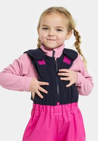 Vaaleanpunainen fleece-zippitakki tummansinisin hihnasa. Kirkkaanpunainen alareuna. Sileä materiaali ja säädettävät sulkijat.