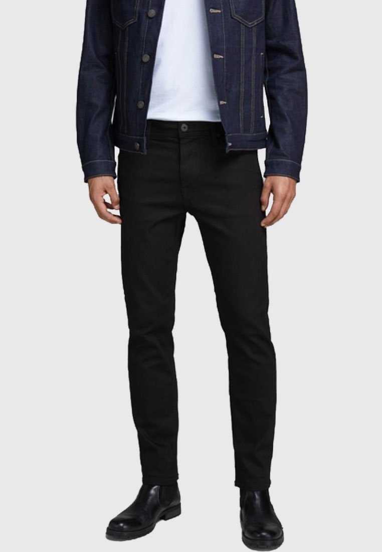 Jeans negros con un diseño ajustado, hechos de mezclilla. Presentan una bragueta con botones, cinco bolsillos y una textura suave. Llevados con una camisa blanca y una chaqueta de mezclilla.