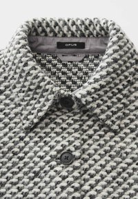 Grau-weiß gemusterter Textilmantel mit Reverskragen, ausgestattet mit zwei Knöpfen und einem Logotag im Kragen.