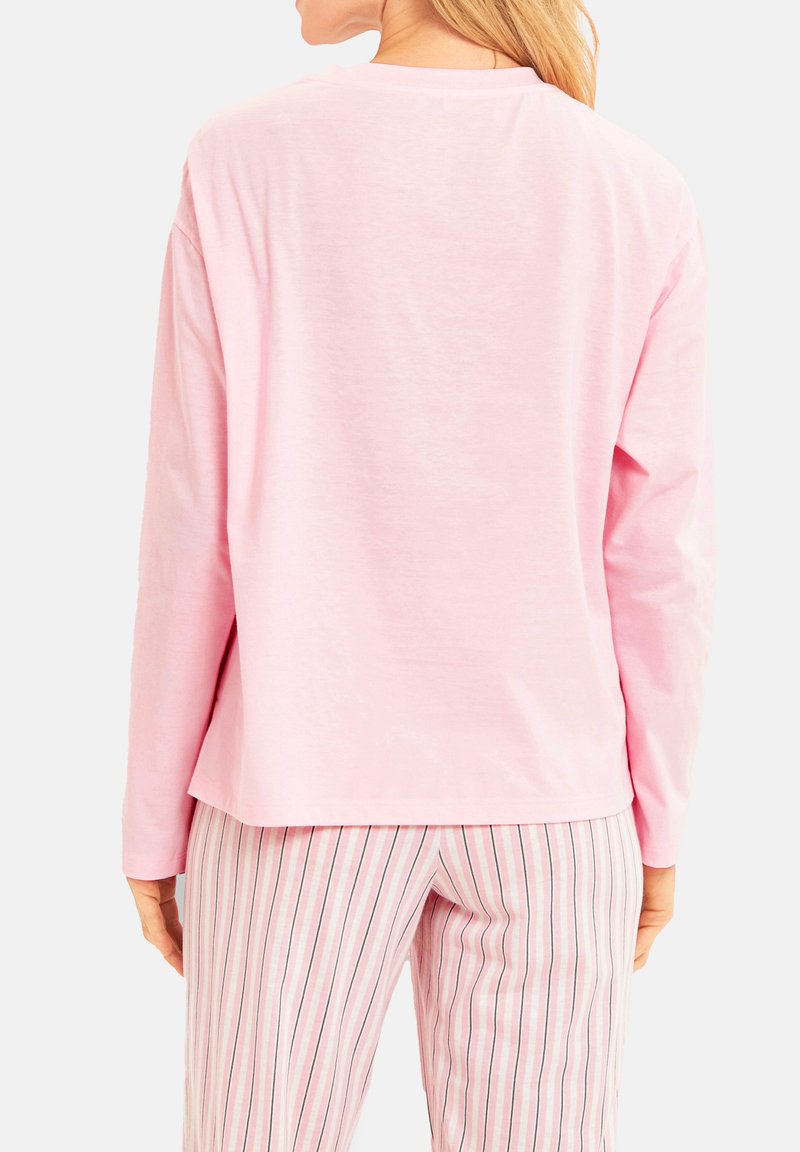 Ljust rosa långärmad topp, mjukt bomullstyg, avslappnad passform, rundad halsringning, ihop med randiga ljusrosa och vita byxor.