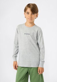 Sivá dlhá rukávová košeľa s okrúhlym výstrihom a logom "CHAMPION" v námorníckej modrej, v kombinácii so zelenými nohavicami. Vyrobená z mäkkej, textúrovanej látky.